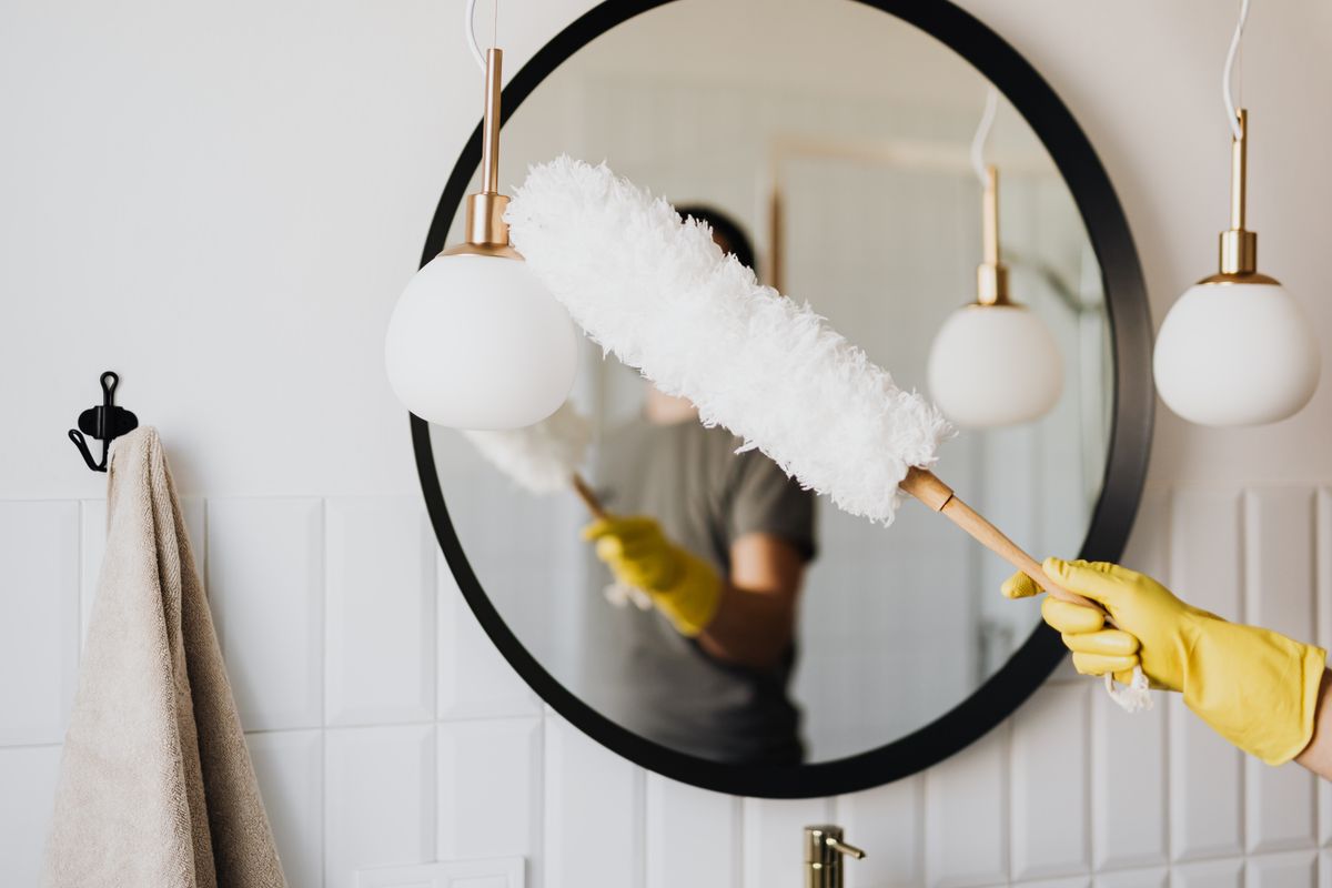 Professional cleaner carefully dusting a finished residential light fixture