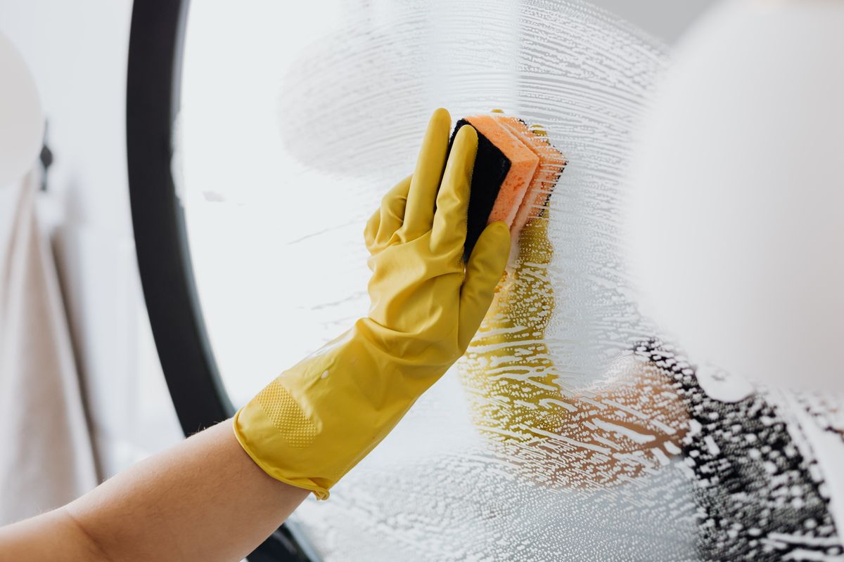 Professional cleaner detailing glass for a streak-free residential handoff